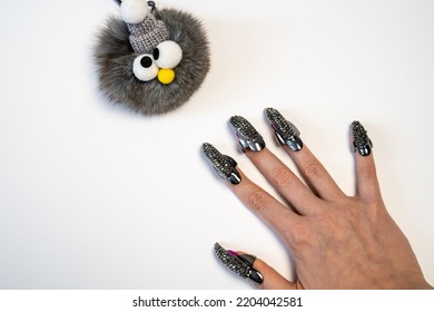 Halloween Theme, Witch Nails, Beautiful Female Hand With Stylish Manicure And Jewellery, Nail Rings, Decoration, Magic, Spooky, White Background, Plush Toy Monster With Eyes 