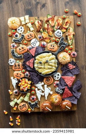 A Halloween themed charcuterie board with candy, cookies and salty snacks.