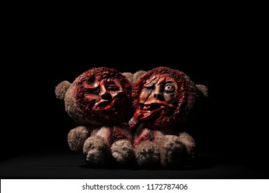 Halloween toy. bears Siamese twins. on a black background. cut faces are visible skulls. bloodstained