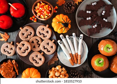 Halloween treat table scene over a rustic dark wood background. Above view. Assortment of candied apples, cookies, candy and sweets. - Powered by Shutterstock