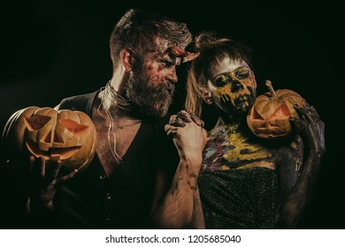Halloween trick or treat concept. Girl with skull makeup face and hipster devil. Woman skeleton and man with horns hold pumpkins. Cosplay, holiday celebration. Couple in love on black background. - Shutterstock ID 1205685040