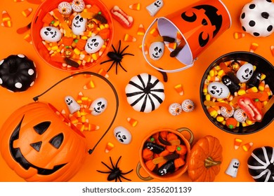 Halloween trick or treat scene with jack o lantern pails and a variety of candy. Top view on an orange background. - Powered by Shutterstock