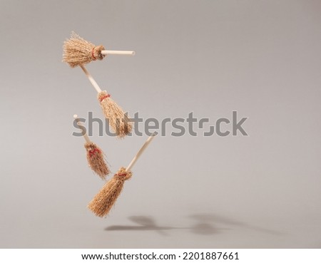 Halloween witch brooms floating against beige background. Witchcraft conceptual backdrop