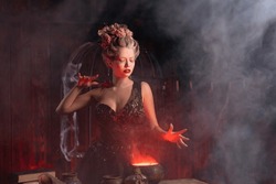 Halloween Witch With Cauldron. Beautiful Young Woman Conjuring, Making Witchcraft. Standing Spooky Dungeon Dark Room. Enchantress Prepare Love Potion Use Magic Spell