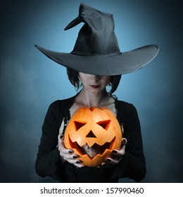 Halloween Witch Holding A Orange Pumpkin, Which Sits Inside A Mouse