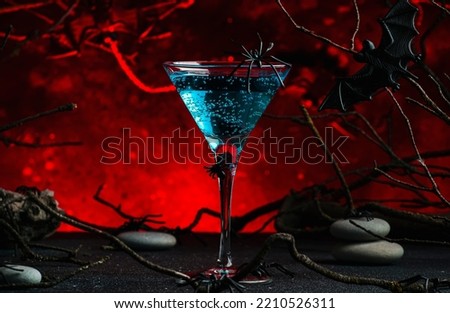 Halloween witch potion alcoholic cocktail on scary dark red background with twisted branches, bats, stones and spiders,  festive drink for party