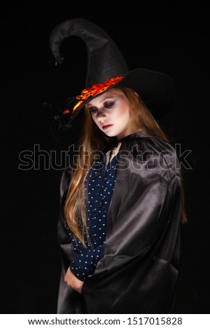 Halloween. Witch with a spider on his hat on black background. Beautiful young surprised woman in witches hat and costume holding. Wide Halloween party art design. Copy-paste. Witch craft concept