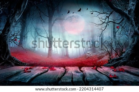 Halloween - Wooden Table In Spooky Forest At Nights With Red Leaves In Autumn Landscape At Moonlight