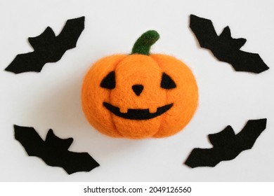 Halloween wool pumpkin and bats on a white background. Felted pumpkin toy. Felting. Top view, flat lay.