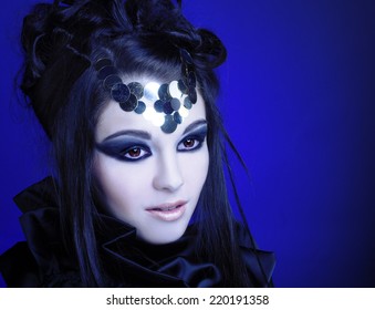 Halloween. Young woman in black dress with artistic visage with smokey-eyes