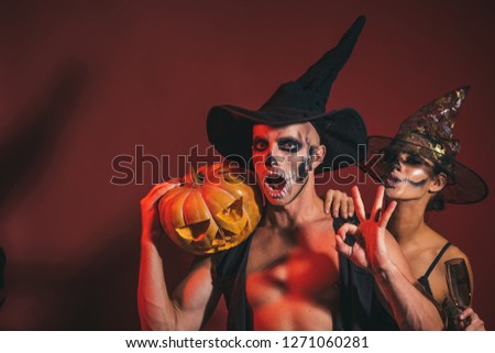 Halloween Zombie party and horror. woman and man has surprised face in witch hat. Holiday and celebration. Couple in love with pumpkin and wine glass. Halloween couple with makeup on brown background.