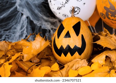 Halloween's holiday attributes. Lantern carved from pumpkin known as Jack-o-lantern on a black background with spider webs, autumn leaves and balloons. Trick or treat. - Powered by Shutterstock