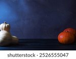 A Halloween-themed still life with pumpkins placed on the sides of the frame. The dark blue background and minimalist composition create a spooky, atmospheric scene perfect for the holiday.