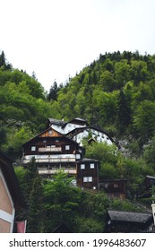 Hallstatt, Austria. Cozy Houses Are Surrounded By High Mountains And Green Forests. Wooden Hotels In The Mountains On A Warm Summer Day. Eco Hotel Among The Austrian Mountains.