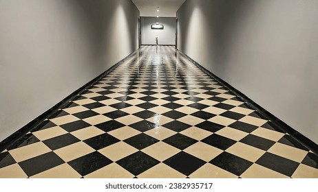 The hallway with black and white checkered tiles on the floor with fire exit sign on wall, Corridor in the building along two doors leading to fire escape. Thailand, November 1, 2023