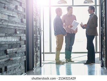 Hallway Brainstorming. Shot Of Male Coworkers Talking While Standing In Front Of A Window In An Office.