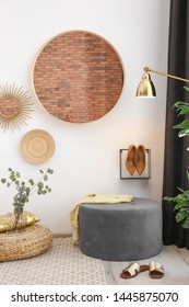 Hallway Interior With Big Round Mirror And Ottoman Chair Near White Wall