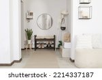 Hallway interior with stylish furniture and round mirror on light wall