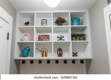 Hallway Mud Room In A New Construction House Home With White Wooden Shelves With Decorative Items, Hooks For Hanging Jackets