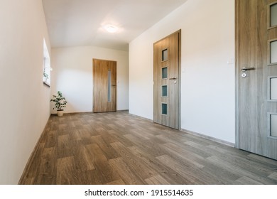 Hallway With Various Contemporary Room Door Designs, Wooden Floor And One Window. All Doors Have A Wooden Texture, Glass Panels Of Various Shapes And Fittings Made Of Matt Stainless Steel. 