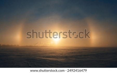Halo effect around the sun during winter sunset over a vast snowy sea landscape