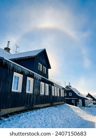 Halo effect in snowy mountains, village with houses, frosty day