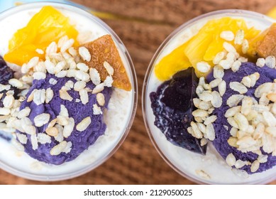 Halo-halo is a popular cold dessert in the Philippines made up of crushed ice, evaporated milk and other toppings. Topped with pinipig and ube , with a straw like wafer added. Top view of two cups. - Shutterstock ID 2129050025