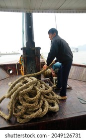 HALONG BAY, VIETNAM - FEB 2, 2015 - Crewman Hauling In The Anchor On Cruise Ship Junk,  Halong Bay, Vietnam