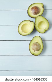 Halved Avocados On A Painted Wooden Kitchen Counter Background