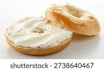 halved bagel is covered with a thick layer of white cream cheese, a simple, tasty meal.