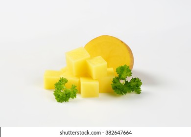 halved and diced raw potato with parsley on white background