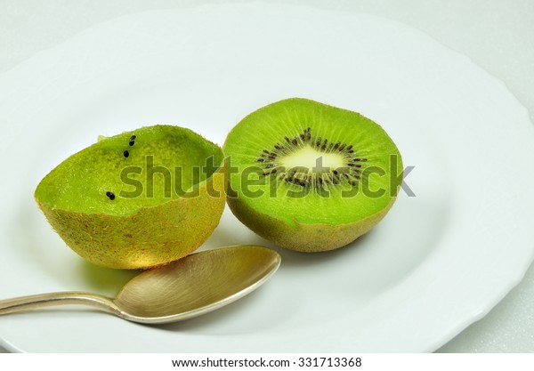 halved\
kiwi fruits, full and empty, on white plate with silver spoon,\
close up, macro, horizontal /Halved Kiwi\
Fruits