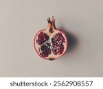 A halved pomegranate with its juicy red seeds visible, resting on a plain, light background. For your background business, poster, wallpaper, banner, backdrop, greeting cards, and advertising 