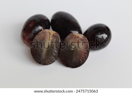 Halved seedless black grape, off the stem, without stalk, isolated on white background