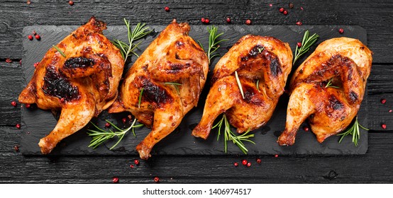Halves of appetizing grilled juicy chicken with golden brown crust served with lemon slices,barbeque  sauce and rosemary. - Shutterstock ID 1406974517