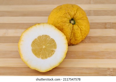 Halves of a citron fruit on a two tone cutting board. Its scientific name is Citrus medica. - Shutterstock ID 2117547578