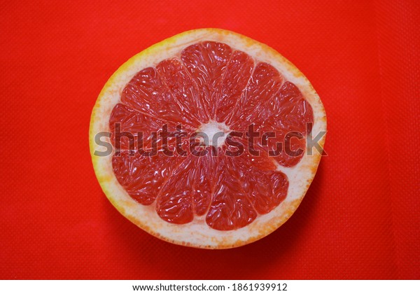 Halves of ripe juicy grapefruit,\
divided in half, placed on a red fabric background. Delicious and\
healthy sweet and sour fruits for the human body and\
health.