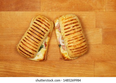 Ham, cheese and onion panini on a wooden chopping board