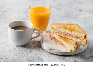 Ham and cheese sandwich, cup of coffee with milk and orange juice glass on concrete table in coffee shop at the morning. Typical breakfast in many countries.  - Powered by Shutterstock