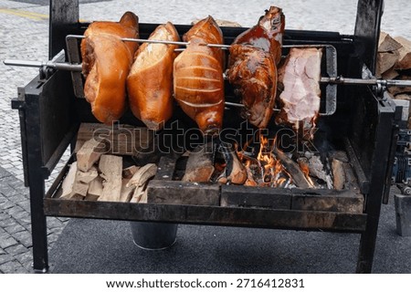 Ham close-up. Appetizing meat is roasted on a spit over an open fire. The golden brown color of the ham shimmers with reflections of juice and fat. The finished ham has a dark baked crust and a very pleasant taste and smell.