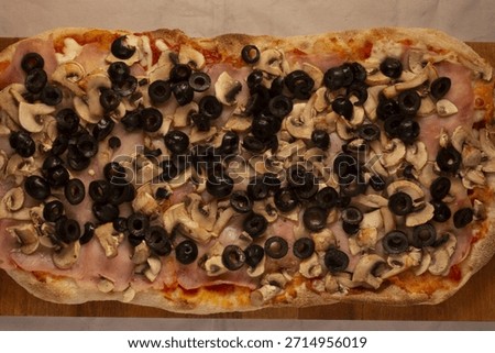ham olive mushroom pizza rectangular on wooden board, black olive slices and sauted mushrooms over melted cheese, communal party