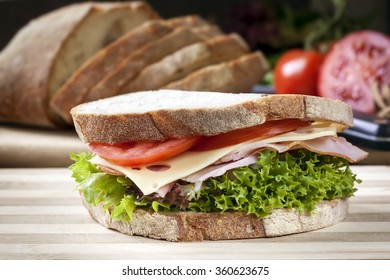 Ham Sandwich With Salad And Cheese.  Loaf Of Bread Behind.