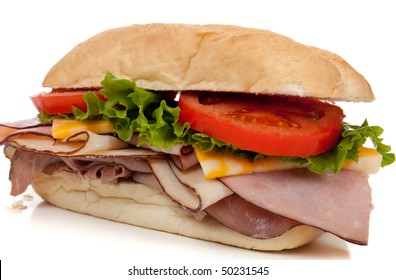 A Ham And Turkey Sandwich On A Hoagie Bun With Lettuce, Tomato And Cheese On A White Background