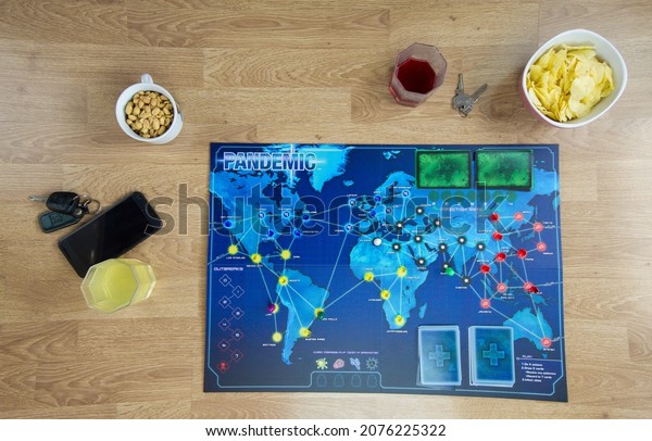 Hamburg, Germany 2.11.21 Board game setup\
for party with snacks and drinks. Pandemic board game and various\
food and drink appetizers on a wooden\
table