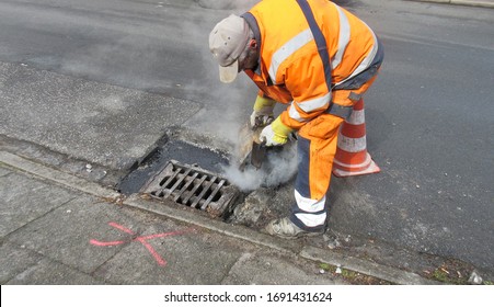 Hamburg, Germany, Europe - 03/30/2020: Road construction, road rehabilitation, asphalting.
A worker in a protective suit pouring boiling hot asphalt into the pothole next to the drain. - Shutterstock ID 1691431624