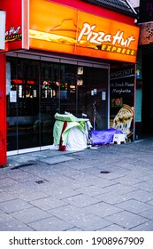 Hamburg, Germany - January 23, 2021 Homeless Person Sleeping In The Entrance Of A Closed Restaurant Of An International Franchise On A Usually Busy Saturday During Corona Lockdown