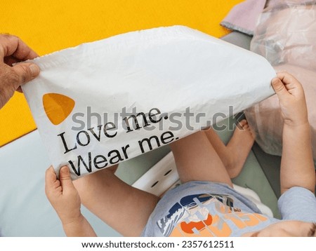 Hamburg, Germany - Jul 24, 2023: Overhead view of adult showing to toddler plastic recyclabe bag with logotype of Zalando and slogan Love Me Weaar me