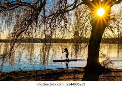 Hamburg, Deutschland - 7. März 2022: Der See Alster bei Sonnenuntergang mit Stehpaddleboarder.