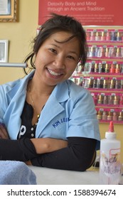 Hamburg, NY /USA - December 12, 2019 : Kim Lee Nails Salon Smiling Asian Young Woman Posing With Nail Polish Bottles In Background