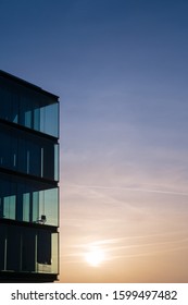 HAMBURG, OEVELGOENNE, HARBOR - 19. December 2019: modern office building glass facade iluminated by a melting sunrise highlighting a single office chair - Shutterstock ID 1599497482